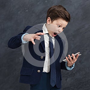 Emotional little boy screaming at smartphone