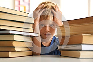 Emotional little boy at table with books. Doing homework