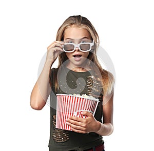 Emotional little girl with cup of popcorn wearing 3D cinema glasses on white background