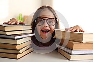 Emotional little girl at table with books. Doing homework