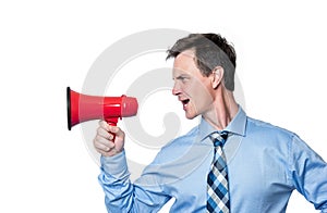 Emotional male businessman in a shirt and tie shouting into a red megaphone, isolated on white background