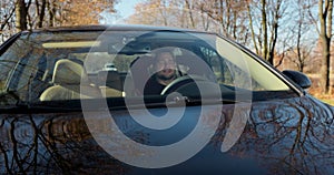 Emotional man in car, view through windshield. Aggressive driving behavior. Angry man driver hitting the steering wheel