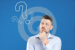 Emotional man with drawings of question marks on background
