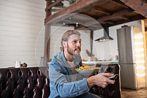 Emotional man eating chips while watching TV