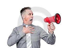 Emotional man holding his hand to his chest and shouting into a red megaphone, isolated on white background