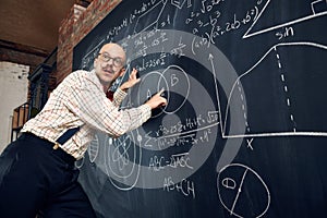 Emotional man, professor, scientist standing by blackboard with scientific formulas and calculations. Math, physics