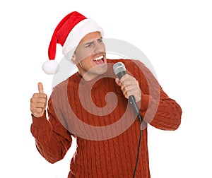 Emotional man in Santa Claus hat singing with microphone on white background. Christmas music