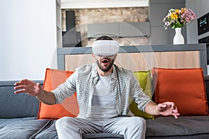 emotional man wearing virtual reality headset while sitting on sofa