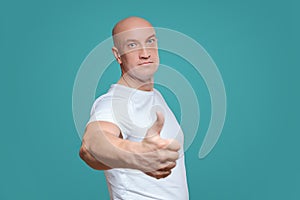 An emotional man in a white t-shirt shows with a hand gesture that everything is cool, on a Titian background