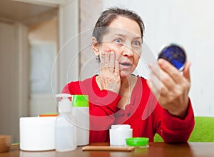 Emotional mature woman stares on face