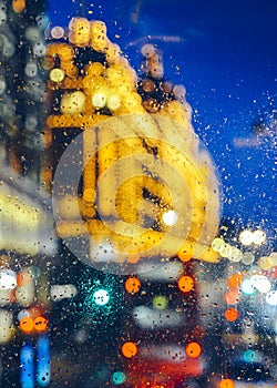 Emotional melancholic abstract background with defocused lights bokeh in London, UK behind rain drops in window glass