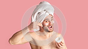Emotional millennial guy funny smears face cream