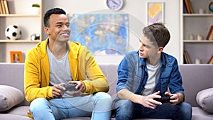 Emotional multiracial male teen friends playing video game, hobby and rivalry