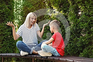 Emotional nanny with cute little boy on bench