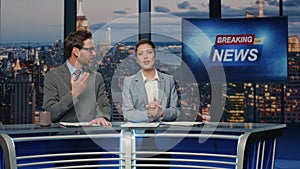 Emotional news readers discussing live tv newscast in night media studio closeup