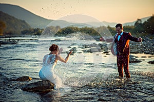 Emotional Outdoor Wedding Portrait Happy Beautiful Smiling Newlywed Couple Playing Splashing Water Having Fun Sunset