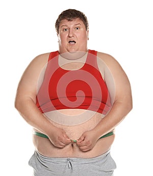 Emotional overweight man measuring waist with tape