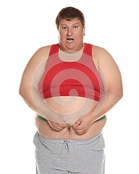 Emotional overweight man measuring waist with tape on background