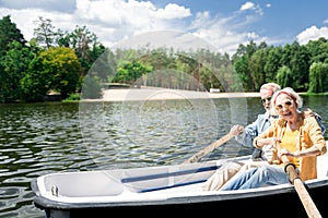 Emotional pensioners holding oars and enjoying boating