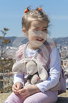 Emotional petite blonde girl 5-7 years old against the backdrop of mountains and Spanish urban architecture