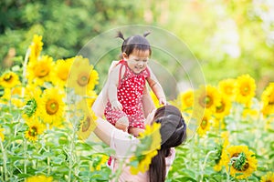 An emotional picture of 1 year old baby and her mother feeling happy together in the sun flower garden.