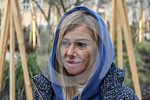 Emotional portrait of a 40-45 year old woman with long dyed hooded hair, emotion of bewilderment or outrage.