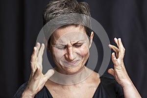 Emotional portrait of an adult woman with short hair and closed eyes. Close-up. Black background