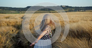 Emotional portrait of the beautiful blonde girl with pretty smile and natural make-up touching golden wheats while