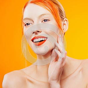 Emotional portrait of beautiful girl with orange hair on orazhevy background