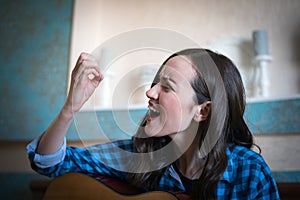 Emotional portrait of a brunette woman broke her nail playing an acoustic guitar. learning music, funny moment