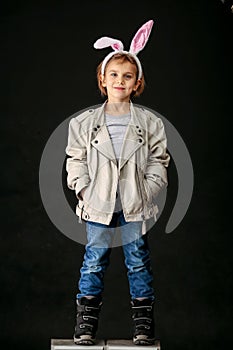 Emotional portrait of a child, a girl in rabbit ears in the studio on a black background