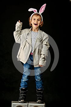 Emotional portrait of a child, a girl in rabbit ears in the studio on a black background