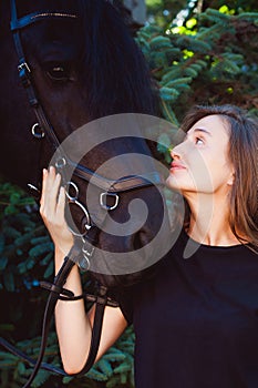 Emotional Portrait of a female in love with horses, black Friesian stallion thoroughbred pet