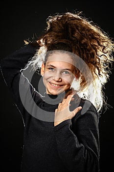 Emotional portrait of a girl with long curly hair on a black background