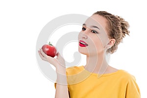 Emotional portrait of a girl with a tomato on an isolated white background in studio. The concept of a healthy diet