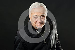 Emotional portrait of a handsome senior man, smiling at the camera, looking joyful and positive. Studio shot of a happy, slightly