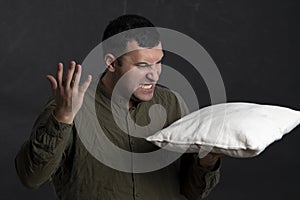 Emotional portrait of a man 30-35 years old, holding a pillow in his hand and screaming. Concept: psychological training, release