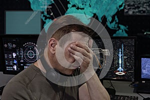 Emotional portrait of a military specialist in headphones, computer monitors. Concept: rocket launch, human observation, analytica photo