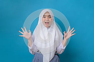 Emotional portrait of scared high school girl looking surprised with fear in her eyes isolated on blue background