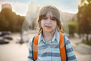 Emotional portrait of a smiling schoolboy with a satchel on his