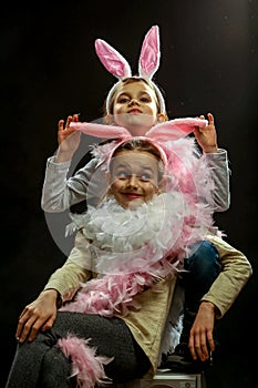 Emotional portrait of two girls, 7-9 years old, in the ears of a rabbit and boa in the studio
