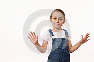 Emotional portrait of a cute baby girl, wearing blue denim overalls, sweetly smiling, showing her hands palms to camera