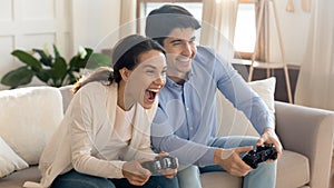 Emotional positive young loving family couple playing online video games.