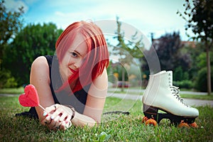 Emotional red-haired girl in a black dress lying on the grass wi