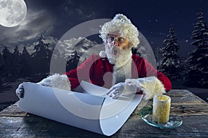 Emotional Santa Claus congratulating with New Year and Christmas, writing a letter, wish list in midnight with candle