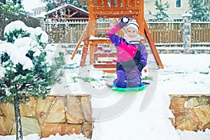 Emotional school age girl plays snow ball fight in winter yard