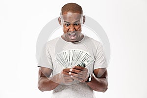 Emotional screaming young african man looking at money.