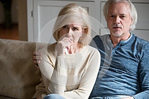 Emotional senior couple get nervous watching TV drama at home