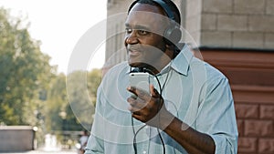 Emotional senior ethnic African American man male listening music in headphones enjoying song audio mobile phone app in