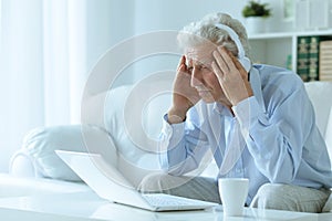 Emotional senior man using laptop at home